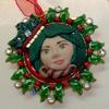 Holly Frame Ornament. Polymer Clay on enameled metal frame. Hinged front opens to reveal photo.
Hand sculpted polymer clay face.